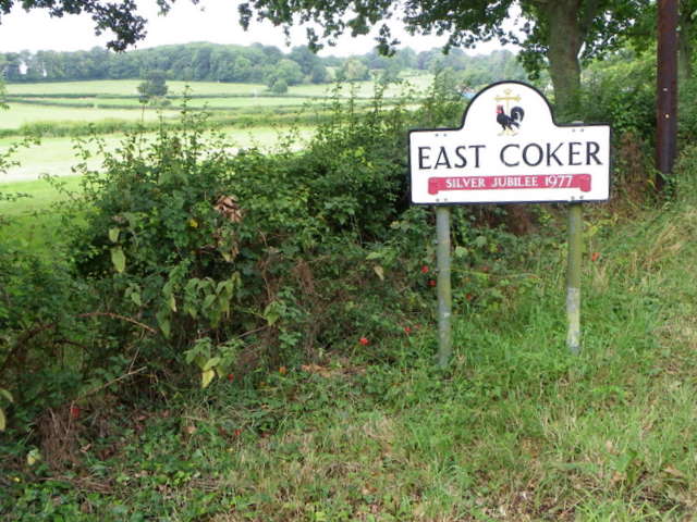 Village sign reading East Coker, Somerset, against green farmland