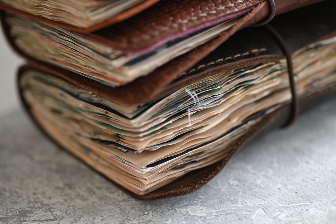 A stack of worn, leather-bound journals and notebooks
